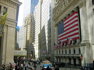 A large flag is stretched over Roman style columns on the front of a large building.