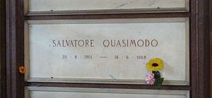 A white marble gravestone on the wall of a chapel, with only the name and dates of birth and death inscribed