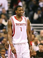 A man, wearing a white jersey with a word "ROCKETS" and the number "1" written in the front, is walking on a basketball court.