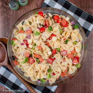 A big bowl of pizza toppings and cooked pasta noodles.