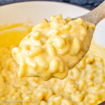 A spoon lifting mac and cheese out of a red pot.