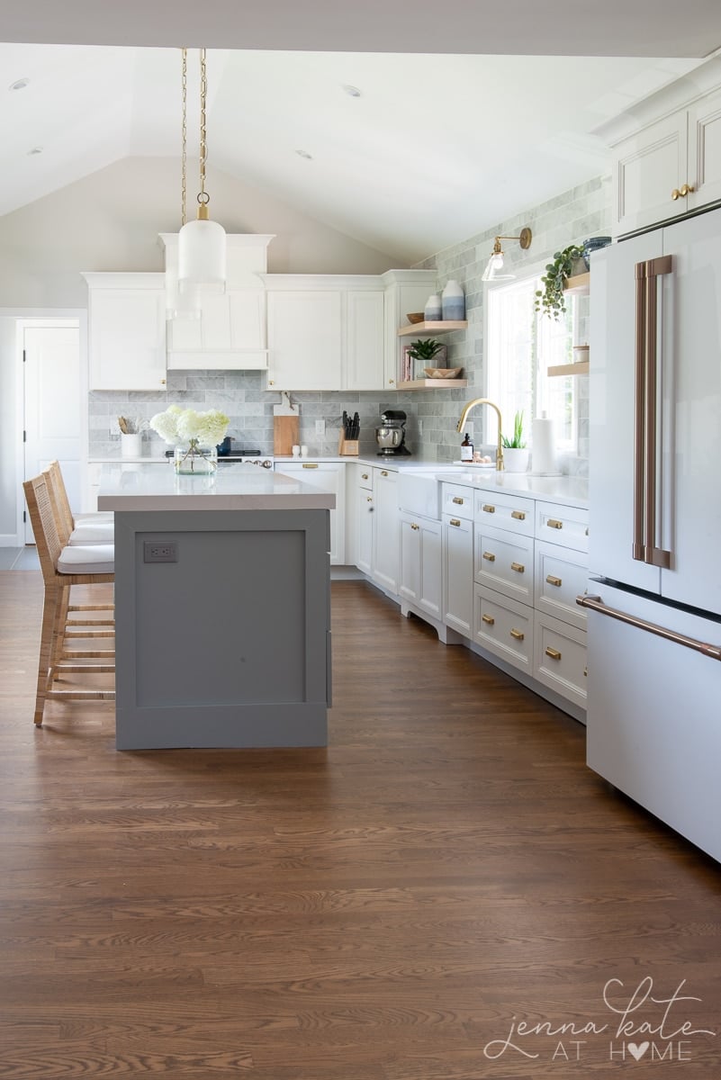 kitchen with white cabinets, blue island and brass accents