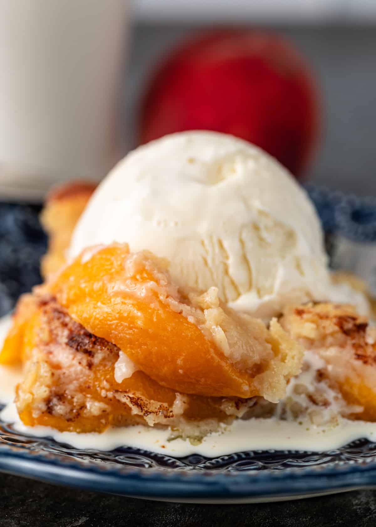 closeup: peach cobbler with a scoop of vanilla ice cream on top