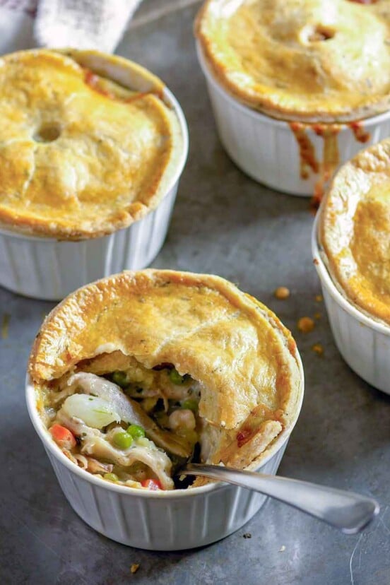 Four bowls filled with chopped chicken and vegetables all topped with golden crusts