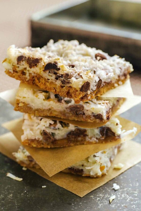 Stack of four Congo bars made of coconut, chocolate, graham crackers, each on a square of paper