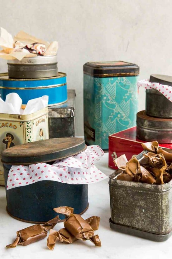 An assortment of holiday cookie tins with tissue paper sticking out of them.