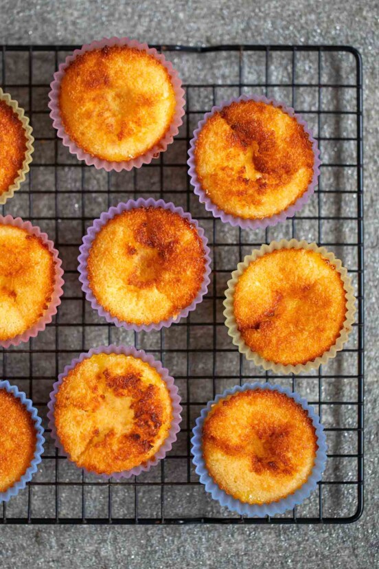 Nine Portuguese coconut custard tarts on a wire rack.