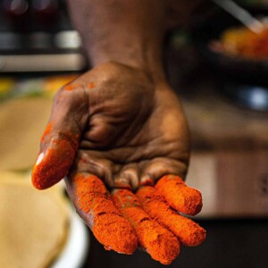 A person's fingers covered in berbere seasoning.