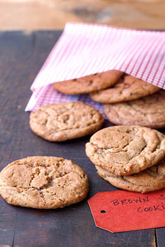 A wooden table with a pink gingham bag with 7 brown sugar cookies in it and a label.