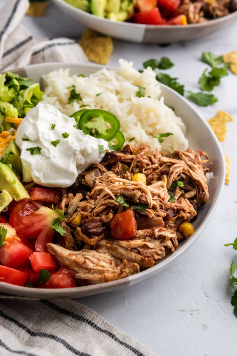 Bowl with chicken tomato, lettuce, and other toppings.