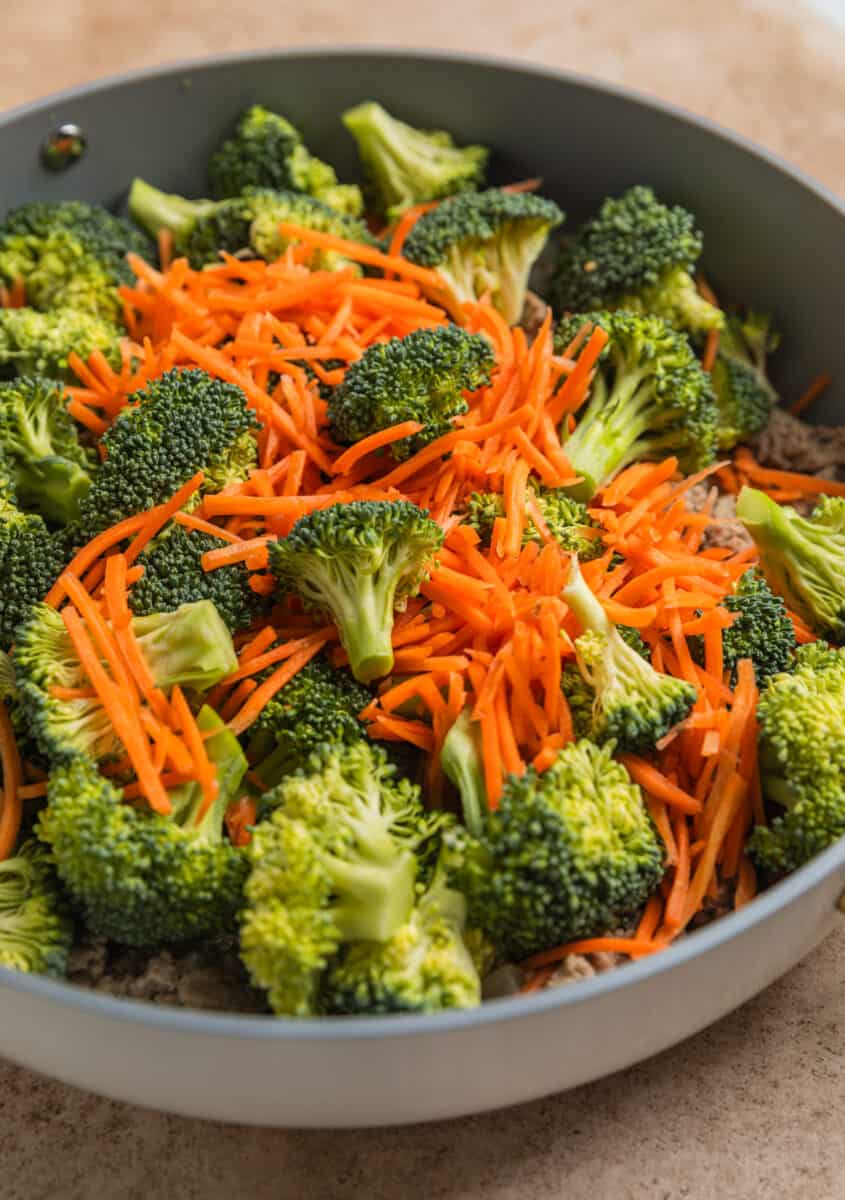 Shredded carrots and broccoli added to skillet with ground turkey teriyaki.