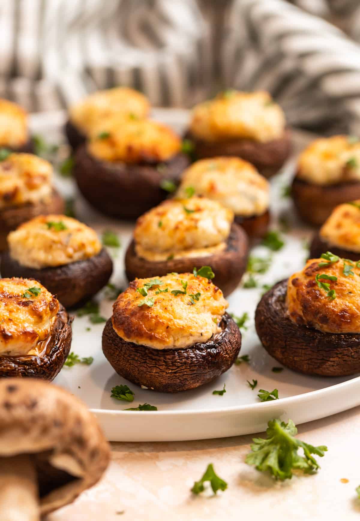 Stuffed baby bella mushrooms with parsley garnish on white plate.