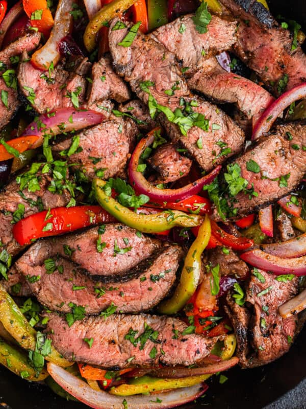 Skillet with steak fajitas topped with cilantro.