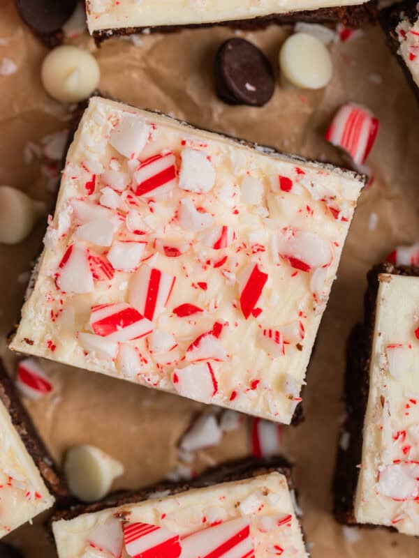 Brownies topped with white chocolate peppermint bark with candy canes and white and dark chocolate chips around them.