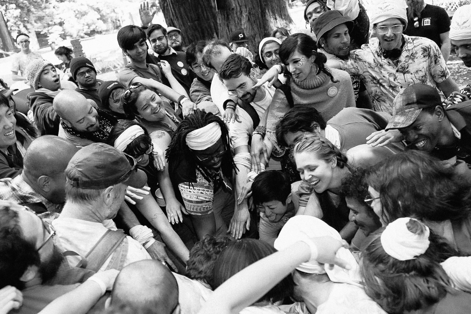 Black and white image of DWeb Campers in a big group putting their hands in the center of a circle.