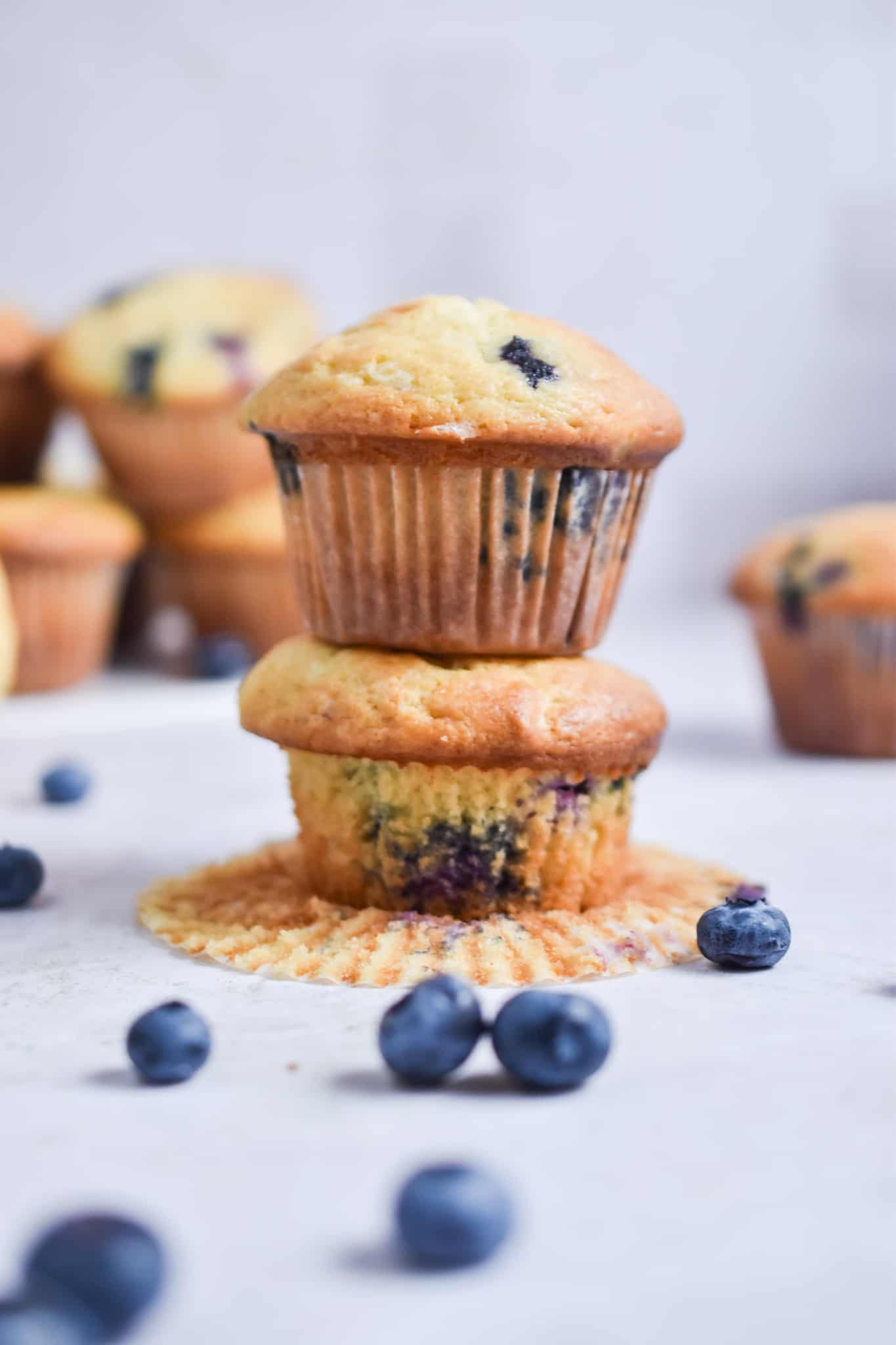 Two blueberry muffins with sour cream are stacked on top of each other.