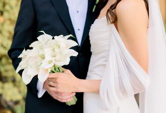 Bride wearing an off-the-shoulder wedding dress with groom beside her