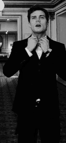 a man in a suit is tying his tie in a hallway .