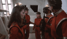 a group of people in red jumpsuits are standing next to each other in a room