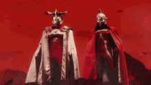 a man in a red cape stands next to a man in a silver cape