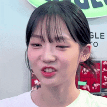 a close up of a young woman making a funny face while wearing a white t-shirt .