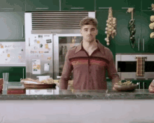 a man in a striped shirt is standing in front of a counter in a kitchen