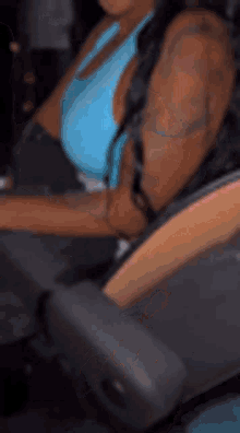 a woman is sitting in a car with a tattoo on her arm .