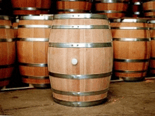 several wooden barrels are lined up in a warehouse