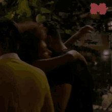 a woman is hugging a man in a dark room with a sticker that says m on it