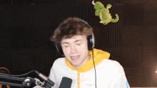 a young man wearing headphones and a yellow hoodie is talking into a microphone