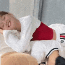 a woman in a red top is laying on top of a man in a white shirt on a bed .