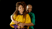 a man in a green shirt and a woman in a yellow sweater are hugging each other