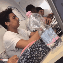 a bottle of sparkling water sits on a desk next to a boy