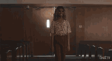 a woman in a leopard print shirt is standing in front of a door with brat tv written on the bottom right corner