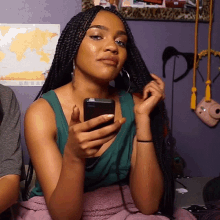 a woman with braids is holding a cell phone