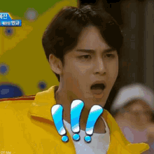 a young man wearing a yellow jacket is making a surprised face .