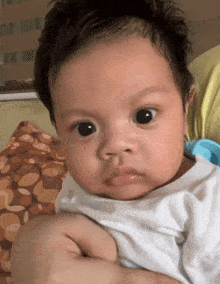 a baby is being held by a person and making a face