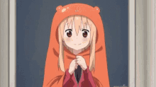 a girl wearing an orange hat is standing in front of a door and smiling .