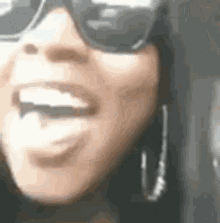 a woman wearing sunglasses and earrings is smiling .