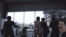 a group of people are standing in front of a window with a monster in the background