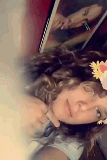 a woman wearing a flower crown looks at a picture of a woman