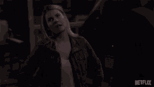 a woman in a leather jacket stands in front of a netflix sign