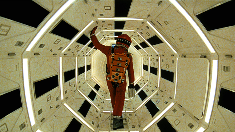 A still from the film 2001: A Space Odyssey of an astronaut in an orange suit walking through a spaceship