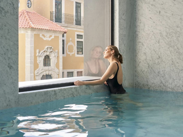 Woman standing by the window while in the indoor pool at PortoBay Flores