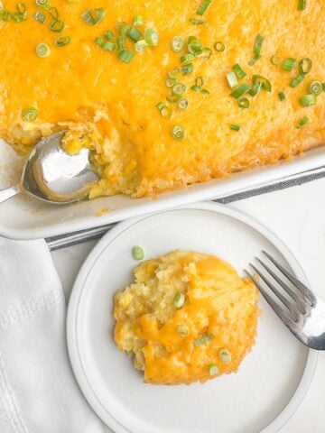 Paula Deen Corn Casserole in a white casserole dish next to a plate of one serving of corn casserole