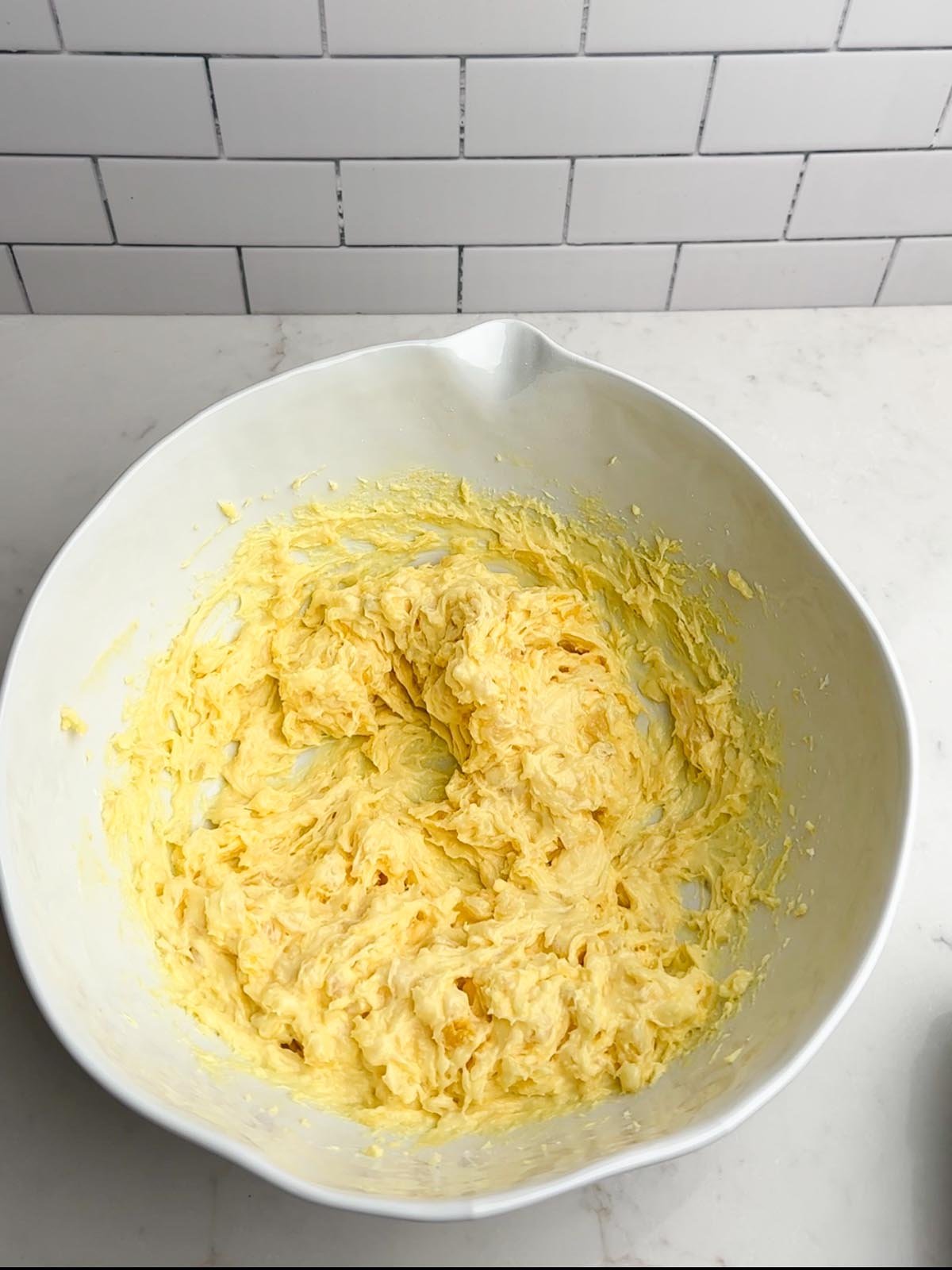 pineapple cream cheese pudding mixture in a white mixing bowl