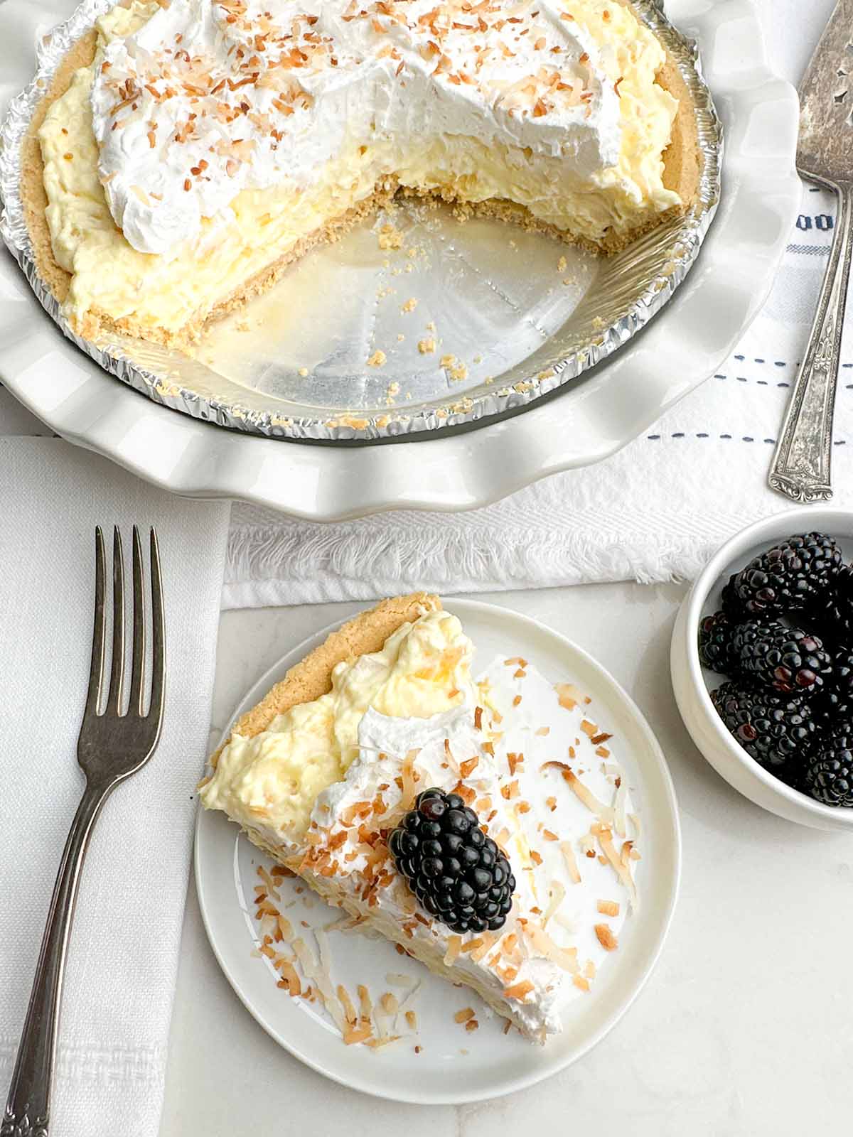 piece of pineapple cream cheese pie on a white plate with partial pie behind it