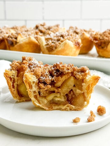 mini puff pastry apple pie cut in half on a white plate