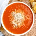 bowl of Rao's tomato soup on a cutting board with a grilled cheese sandwich.