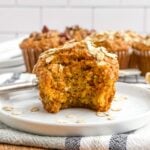 banana carrot muffin with a bite taken out on a white plate.